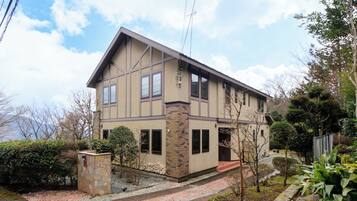 A two-story house with a stone pillar, a small garden, and a view of the sky.