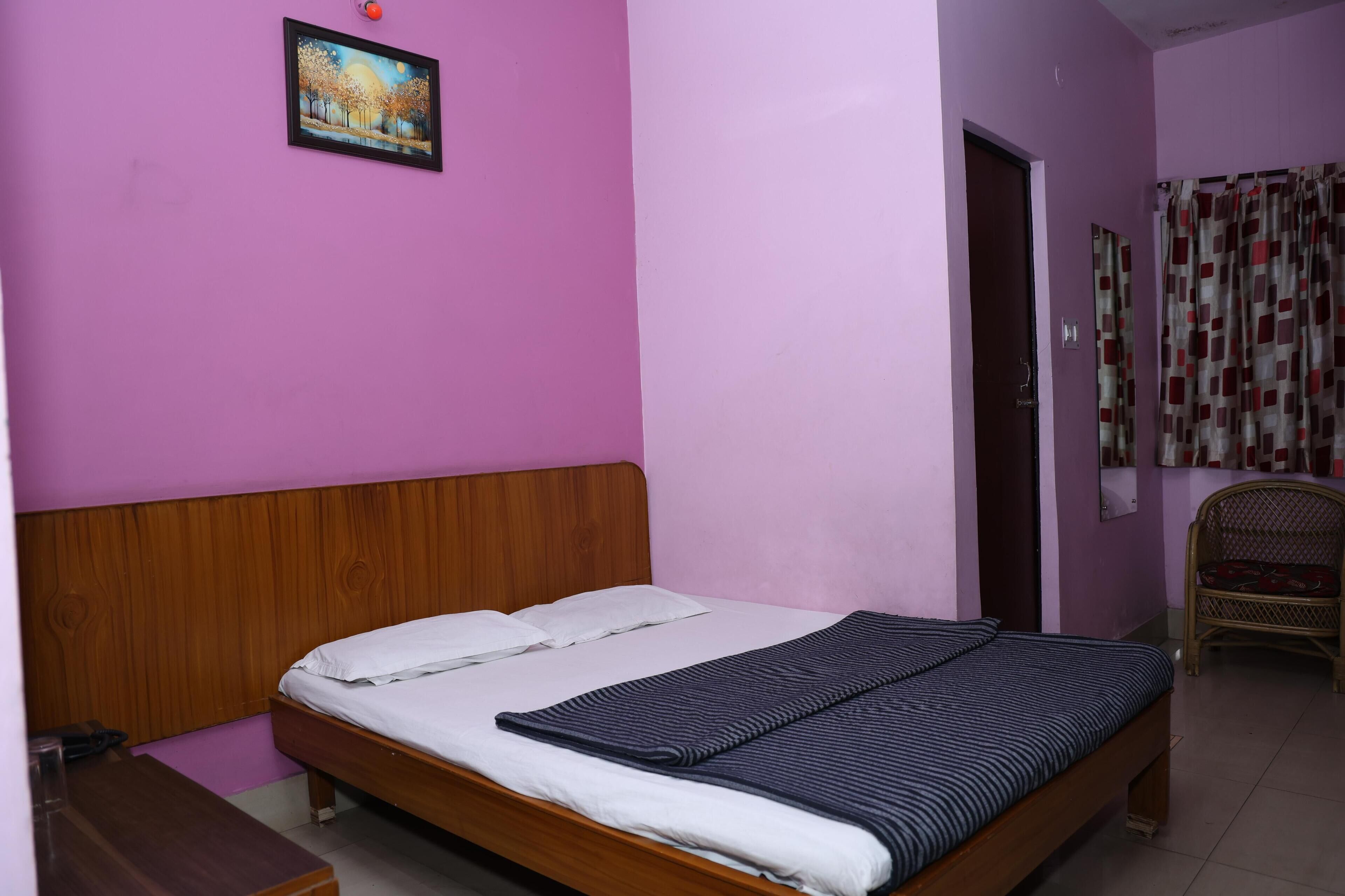 A room with a wooden bed, a small table, a picture on the wall, and a door with a curtain.