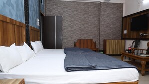 A neatly made bed with white linens, a wooden headboard, and a folded blanket. - Hotel Hill View (Jamshedpur)