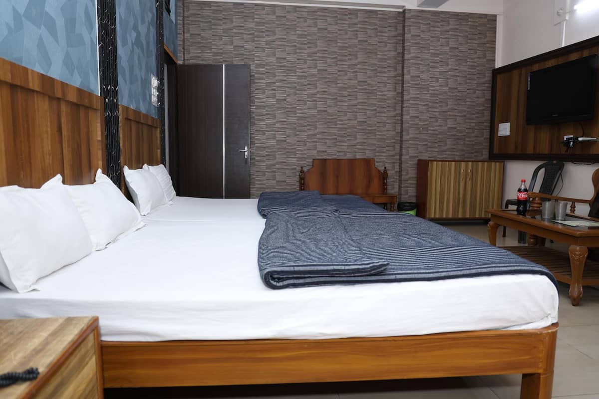 Una cama bien hecha con sábanas blancas, cabecera de madera y una colcha doblada.