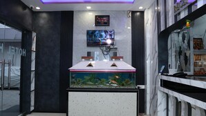 A reception area with a fish tank, a digital clock, and a television. - Hotel Hill View (Jamshedpur)