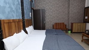 A hotel room with a large bed, a wooden wardrobe, a wooden chair, and a small table. - Hotel Hill View (Jamshedpur)