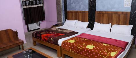 A hotel room with two beds, a wooden headboard, a window with curtains, a small table with glasses, and a chair.