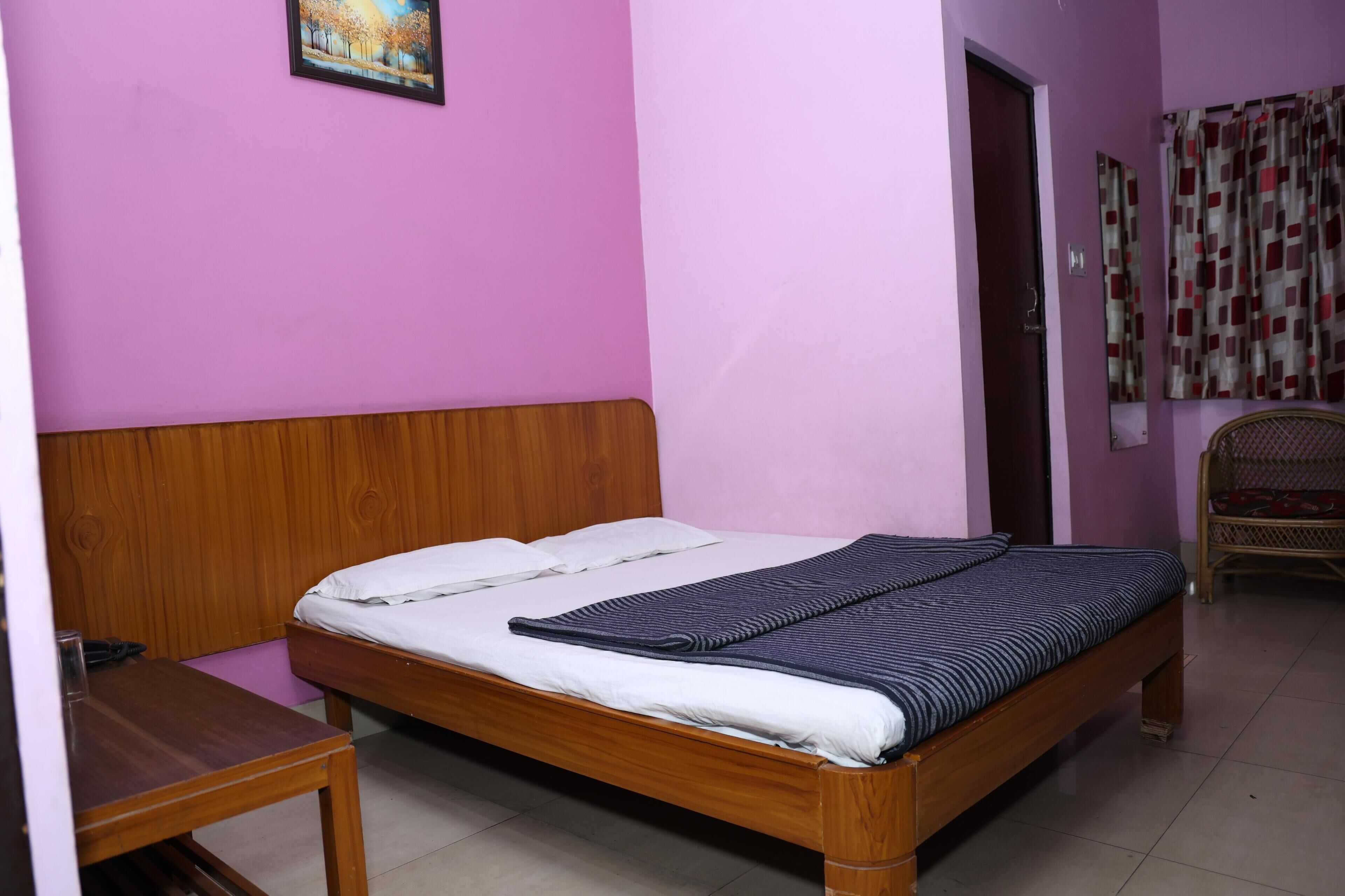 Un dormitorio con una cama de madera, una mesita pequeña y una silla.