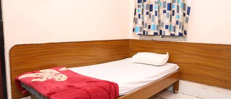 A single bed with a wooden frame, a white mattress, and a red blanket.