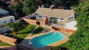 A residential property with a swimming pool, a covered patio, and a brick wall.
