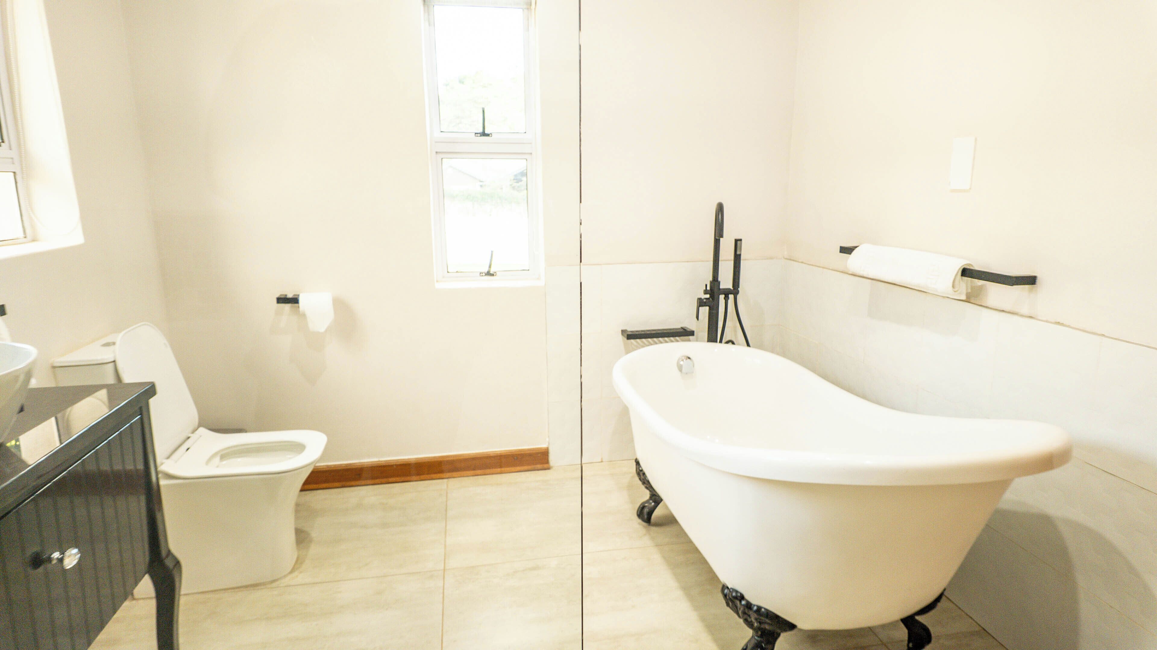 Une salle de bain comprenant des toilettes, une baignoire, un lavabo et une fenêtre.