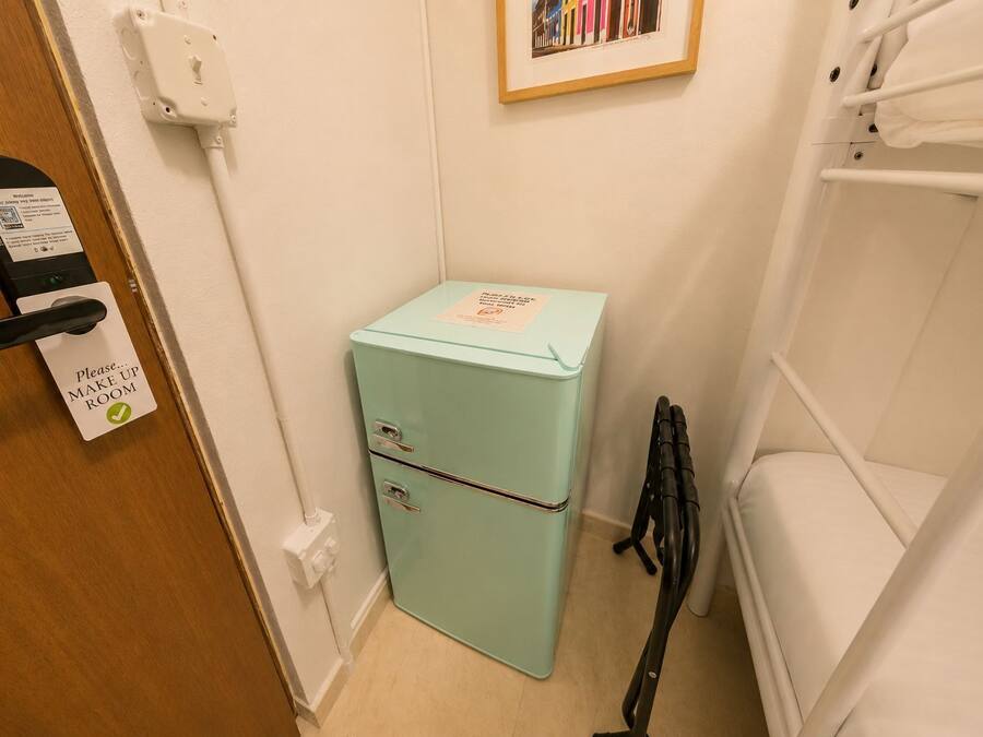 A compact room with a vintage teal refrigerator, a white sink, and a white shower.