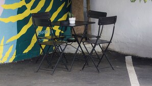 A tree with green mangoes, a mural with yellow and blue patterns, and a table with chairs. - Room 4: Compact Bunk Room in Arts District (San Juan)