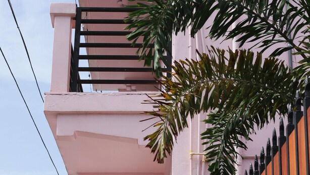 A pink building with a balcony, a gated entrance, and parked cars along the street. - Room 4: Compact Bunk Room in Arts District (San Juan)