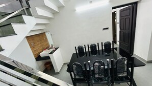 Una cocina moderna con encimera blanca, un mueble de madera y una mesa de comedor negra con sillas.