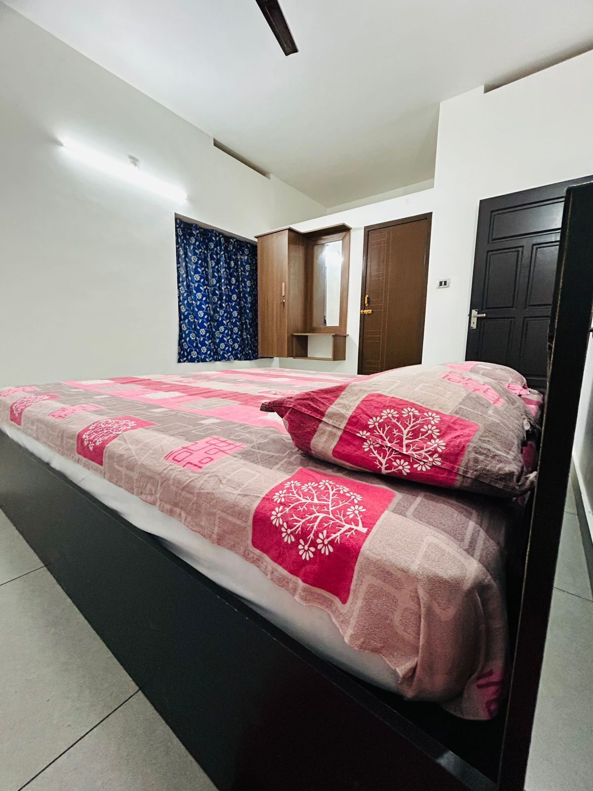 Ein Schlafzimmer mit Bett, Kleiderschrank, Spiegel und Tür.