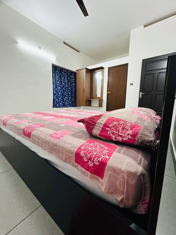 A bedroom with a bed, a wardrobe, a mirror, and a door.