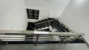 Una escalera moderna con barandales de metal y un pequeño ventanal en la parte superior.