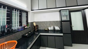Cocina compacta con encimera negra, estufa, pileta y ventana con persianas.
