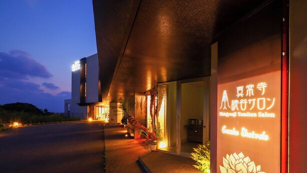 Un bâtiment moderne orné d’une enseigne au néon indiquant « Shinjyujyoji Yomitan Salon ».