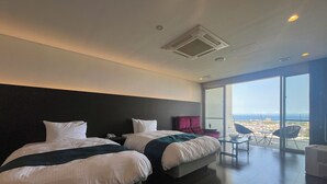 Une chambre d’hôtel avec deux lits, une grande fenêtre donnant sur un beau paysage et un balcon avec des chaises.