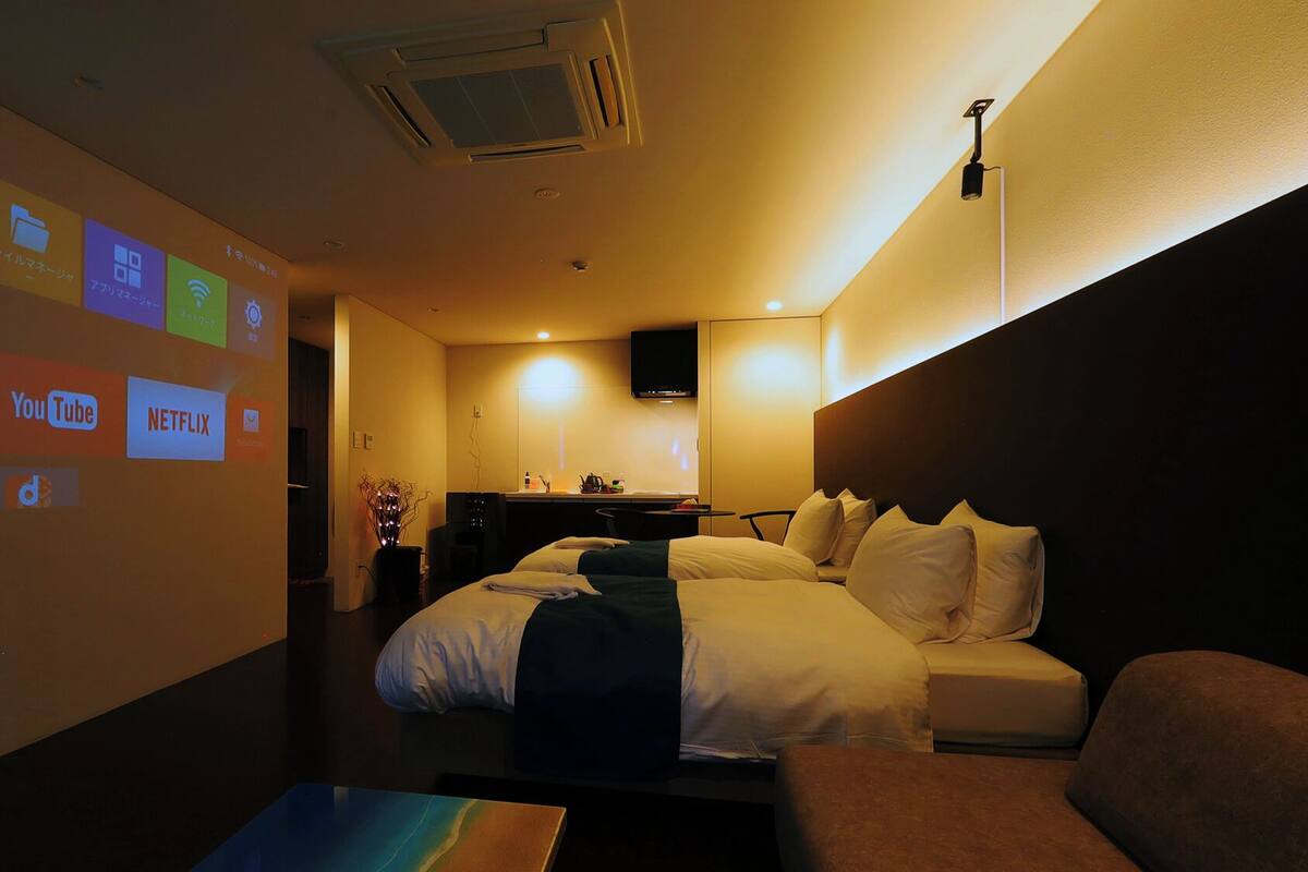Ein Hotelzimmer mit Bett, Schreibtisch und Projektor, der Serviceleistungen anzeigt.