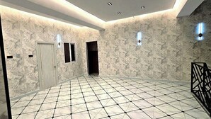 A spacious hallway with a patterned floor, a white door, and a staircase with a geometric railing. - Best hotel (Tashkent)