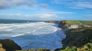 A coastal landscape with cliffs, a beach, and a small settlement. - Luxury caravan, Newquay Bay. Amazing views. (Newquay )