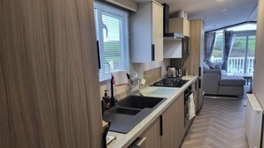 A modern kitchen with a large island, built-in appliances, and a view to a balcony. - Luxury caravan, Newquay Bay. Amazing views. (Newquay )