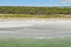 A beach with sand and water, a forest in the background, and a clear sky. - Holiday home near the beach perfect for relaxing (Nexø)