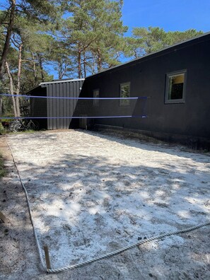 A building with a covered area, a rope boundary, and trees in the background.