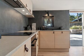 A modern kitchen with a large island, built-in oven, and a window above the sink.