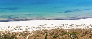 A coastal landscape with a sandy beach and sparse vegetation.