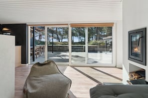 A modern living room with a large sliding glass door leading to an outdoor patio, a fireplace, and a seating area with a bean bag and a couch.