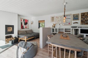 A modern interior with a fireplace, seating area, dining table, and various wall decorations.