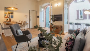 A modern living room with a dining area, large windows, and a balcony. - The Printers Home 2 by Rent all Como (Como)
