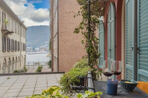 Una terrazza con vista sul mare, un tavolo con due bicchieri di vino rosso e una candela.