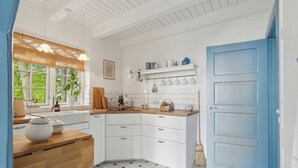 A kitchen with white cabinets, a blue door, and a tiled floor.