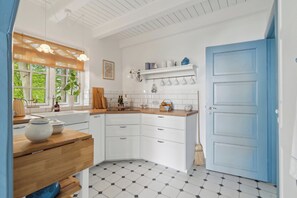 A kitchen with white cabinets, a blue door, and a tiled floor.