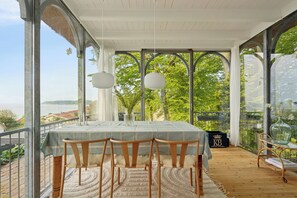Un espace repas comprenant une table, des chaises et une vue sur la mer.