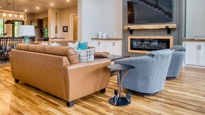 A spacious living area with a large sofa, a coffee table, and a TV mounted on a wooden wall. - Family House on Watauga River (Johnson City)