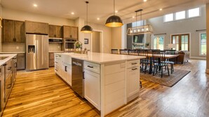 A spacious kitchen with wooden cabinets, stainless steel appliances, and a central island with seating. - Family House on Watauga River (Johnson City)