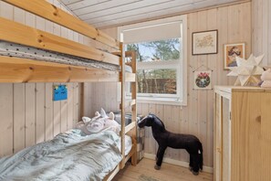 Et værelse med køjeseng, et vindue, en hestefigur og et lille skab.