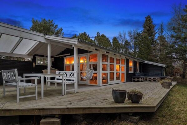 A wooden deck with outdoor seating, a hanging chair, and a large planter.