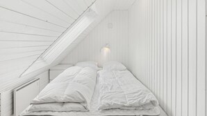 A small, white, attic-style bedroom with a sloped ceiling, a single bed, and a wall-mounted light fixture. - "Poul" - 1.9km from the sea by Interhome (Blåvand)
