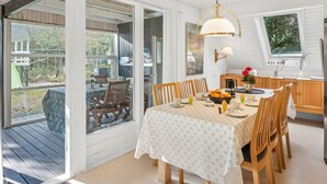 A dining area with a table set for four, surrounded by wooden chairs. A chandelier hangs above the table, and a window provides a view of the outdoors. - "Poul" - 1.9km from the sea by Interhome (Blåvand)