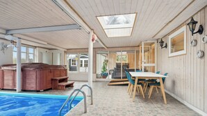 A pool area with a hot tub, a dining table with chairs, and a view of the outside.