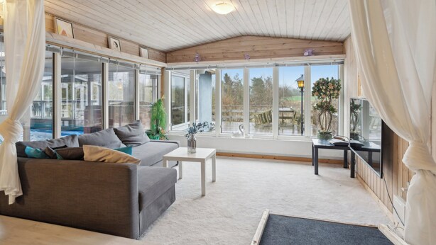 A spacious room with a large window, a sofa, a small table, and a view of the outdoors.