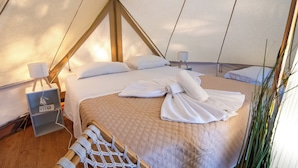 Ein zeltartiges Zimmer mit einem Bett, zwei Nachttischen mit Lampen, einer Steckdose und einer Seilleiter.