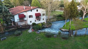 Ein weißes Gebäude mit roten Markisen, ein Fluss und eine Brücke.