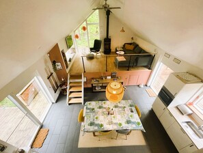 Un espacio habitable compacto y de varios niveles, con comedor, cocina y habitación en altillo.