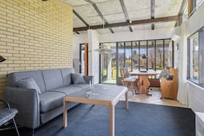 A modern living room with a sofa, coffee table, and dining area. - Cozy cottage near Bjerge Strand (Store Fuglede)