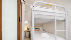 A bunk bed with a headboard, a bedside table with a lamp, and a small potted plant. - Room 6: Affordable Cool in Santurce Arts Area (San Juan)