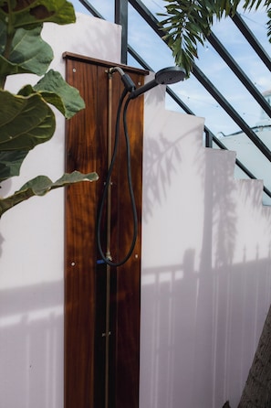 Un cerramiento de ducha con puerta de madera y una manguera adherida a la pared.